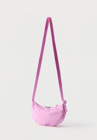 Világos lila, félhold alakú válltáska, állítható pánttal és felül cipzáras záródással, egyszerű fehér háttér előtt bemutatva.