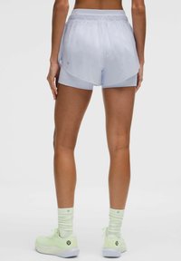 Pantalones cortos de running en azul claro con diseño en capas, cinturilla elástica y tejido suave. Combinados con zapatillas en verde menta y calcetas acanaladas.