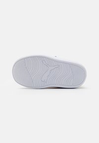 Suela de zapatilla de goma blanca con un patrón texturizado que presenta surcos y un logo. Acabado suave con un diseño minimalista.