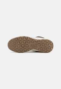 Brown and white sneaker with a textured rubber outsole featuring a geometric pattern. Logo embossed on the heel. Smooth upper materials.