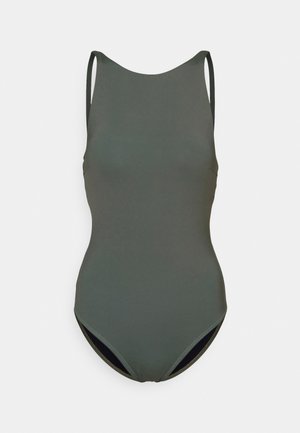 Tumedast rohelisest ühes tükist ujumistrikood, millel on õhukesed rihmad ja sile tekstuur. Omab lihtsat, klassikalist disaini ning keskmise lõikega jalalõike.