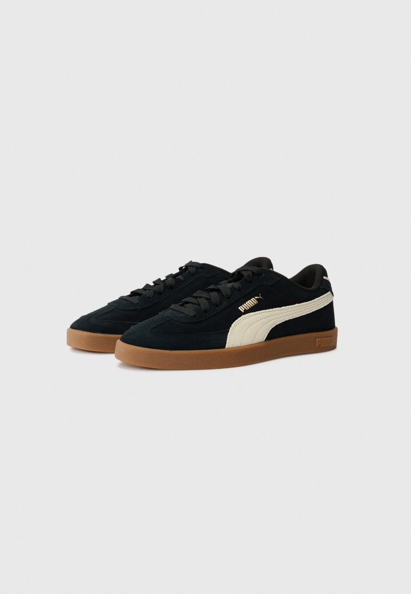 Sneakers in suede nero con una striscia laterale color crema, dotati di suola in gomma marrone e lacci neri. Marchio sul lato e sul tallone.