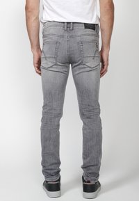 Šedé džíny se slim fit, se dvěma zadními kapsami, jemným oděrem a kontrastními švy. Nosit s černými teniskami.