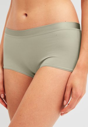 Gros plan d'une personne portant un shorty sans coutures de couleur vert clair, montrant la taille, les hanches et le haut des cuisses.