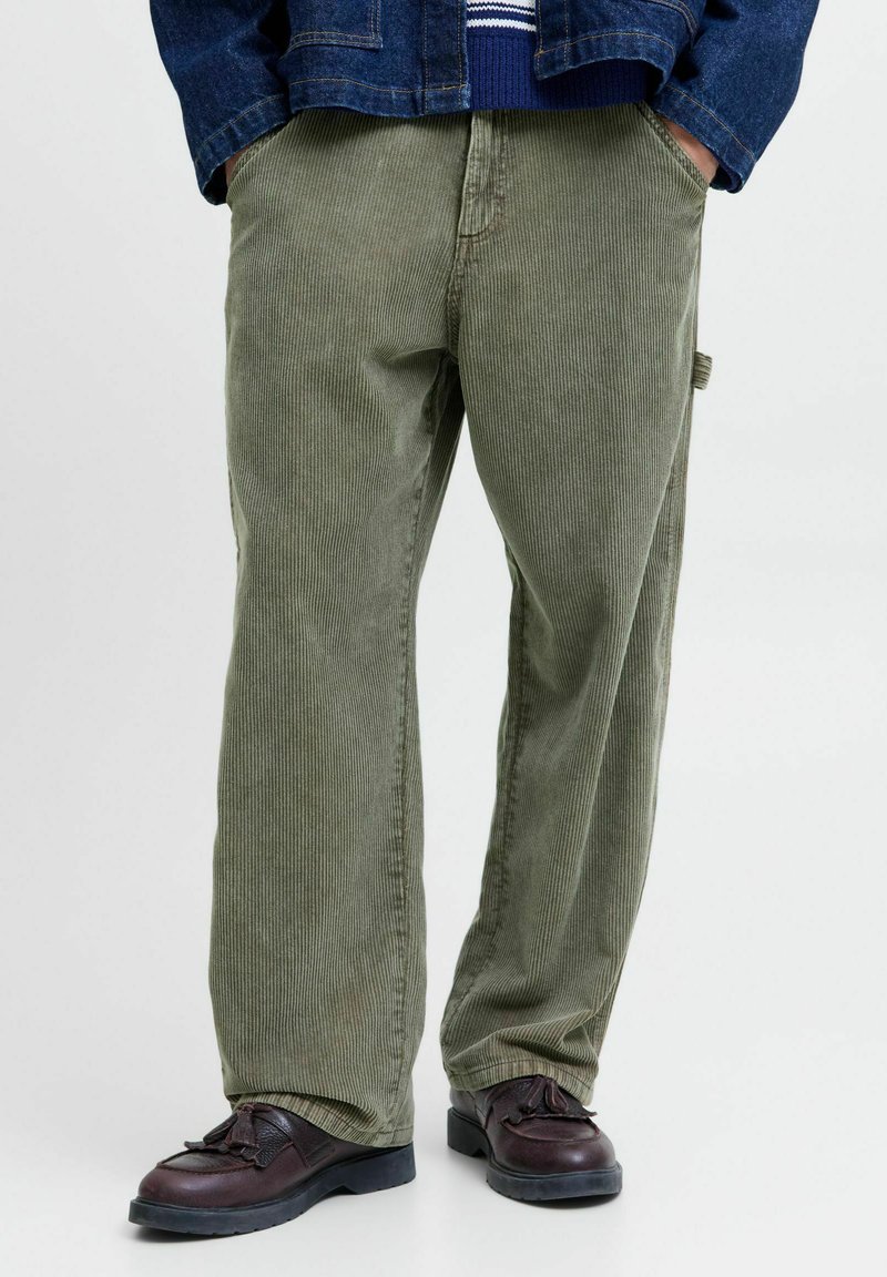 Grønne cordbukser med rett ben, med vertikale striper og en sidelomme, kombinert med mørke sko.