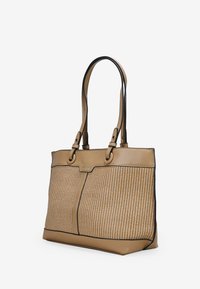 Bolso tote beige con textura de paja trenzada, acentos de cuero y ribetes negros. Dos asas resistentes con herrajes metálicos para soporte y durabilidad.