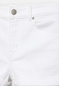 Short en denim blanc avec bouton métallique, passants de ceinture, poche avant et détail d'ourlet roulé sur fond uni.