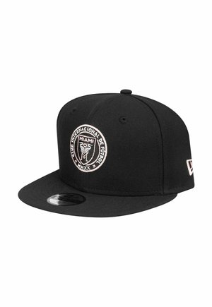 Une casquette de baseball noire en tissu présente un logo rond brodé avec "Club Internacional de Fútbol Miami" en rose et "MMXX" en dessous.