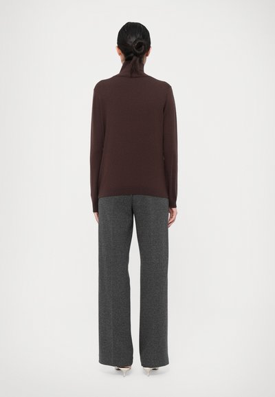 Pull en maille marron avec un col montant, associé à un pantalon large gris. Les deux vêtements présentent des textures douces et des coupes confortables.