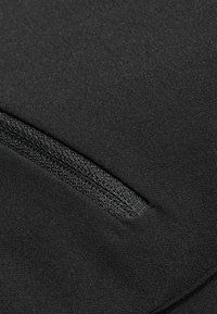 Tissu noir avec une surface texturée et une poche zippée visible. Le matériau semble lisse et élastique, adapté aux vêtements de sport.