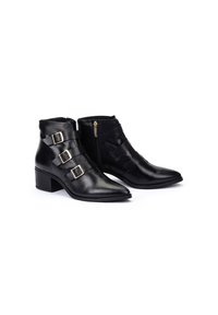 Botines de cuero negro hasta el tobillo con puntas afiladas, tacones apilados y tres detalles de hebilla; cuentan con una cremallera lateral y una textura suave.