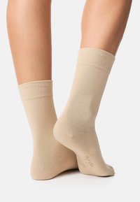 Beige ankelstrømper lavet af et blødt stof, med en ribbet kant, glat tekstur og forstærket tå for holdbarhed.