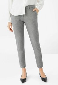 Grau, maßgeschneiderte Hose mit glatter Textur und schmaler Passform. Verfügt über einen flachen Bund und Seitentaschen. Kombiniert mit schwarzen spitzen High Heels.