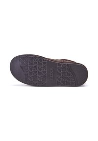 Suela de zapato marrón oscuro con una superficie de goma texturizada que presenta patrones circulares y geométricos, con la marca "AUSTRALIA LUXE COLLECTIVE."