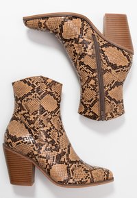 Tan snake-print ankle boots with a textured finish, tapered toe, and stacked block heel. Features a side zipper for easy wear.