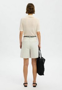 Top en crème léger à côtes, à manches courtes, associé à un short tailleur gris clair et un sac fourre-tout tissé noir.