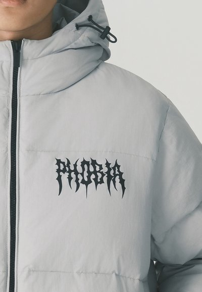Giubbotto trapuntato grigio chiaro con colletto alto, caratterizzato da un logo nero "PHOBIA". Il materiale è liscio, con una texture trapuntata e cappuccio regolabile.