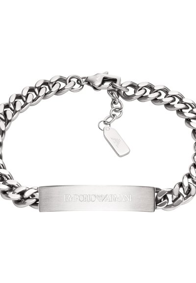 Bracelet en chaîne métallique argentée avec une plaque plate gravée "EMPORIO ARMANI" et une petite étiquette avec un logo attachée.