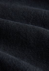 Sötét farmeranyag sima textúrával és finom átlós szövési mintával, mély kék-fekete színben.