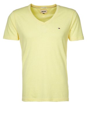 T-shirt jaune à manches courtes en V fabriqué en coton léger et doux. Présente un petit logo brodé sur la poitrine. Design basique, coupe classique.