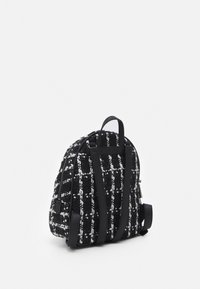Czarnobiały plecak z tweedu o teksturowanej tkaninie, skórzanych paskach i górnym uchwycie. Zaokrąglony kształt, boczny zamek błyskawiczny i charakterystyczny wzór w kratę.