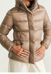 Beige pufferjakke med quiltet design, hætte og justerbare snore. Har trykknapper og sidelommer. Glat, skinnende tekstur.