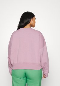 Lös passform påpullover i mjuk lavendelfärgad väv, med rund halsringning och sänkta axlar. Har en bred fåll och långa ärmar.