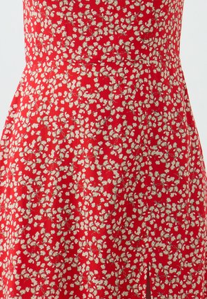 Rode jurk met een bloemenpatroon met kleine witte bloemen en groene accenten. Gemaakt van lichtgewicht stof met een zachte textuur.