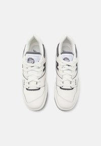 Hvite New Balance 550 sneakers har en skinnoverdel, grå detaljer, snøring og logo på tungen, med en teksturert gummisåle.