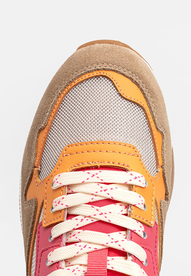 Zapatilla colorida con materiales de ante y malla, en tonos marrón, naranja, rosa y crema. Cordones planos y estampados con ojales reforzados.