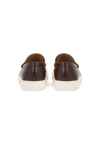 Zapatos de cuero marrón tipo mocasín con perfil bajo, suelas de goma blanca y textura suave. Diseño minimalista sin hardware visible ni patrones.