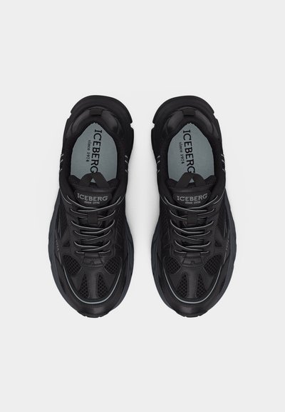 Ζευγάρι μαύρα αθλητικά παπούτσια της μάρκας ICEBERG με λεπτομέρειες από δίχτυ και ανακλαστικές ρίγες, φωτογραφημένα από πάνω σε απλό φόντο.