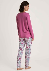 Lange mouwen roze top gecombineerd met bloemenpatroon broek in lavendel, roze en blauw, met een losse pasvorm en zachte textuur.