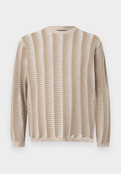 Pull en maille à manches longues beige et blanc avec un motif, col rond, poignets et ourlet côtelés, présenté sur un fond uni.