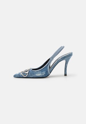 Jeans Slingback-Pumps mit spitzem Zehenbereich, silbernem Hardware-Detail, hellblauer Farbe und strukturiertem Stoff. Die Rückseite des Absatzes hat ein dezentes Streifenmuster.