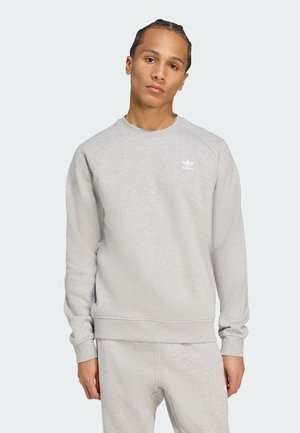 Felpa grigia chiaro con scollatura rotonda e polsini a costine, presenta un piccolo logo Adidas bianco sulla parte sinistra del petto.
