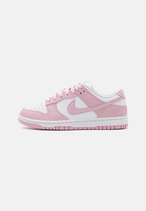 Lage sneaker met roze ribfluwelen overlays, witte lederen panelen, roze veters en een roze rubberen zool op een witte achtergrond.