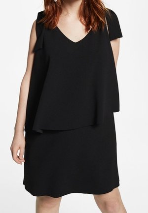 Schwarzes Kleid mit V-Ausschnitt, geschichteter Obergestaltung und kurzen Ärmeln. Weicher Stoff mit fließender Silhouette und einem gewellten Saum.