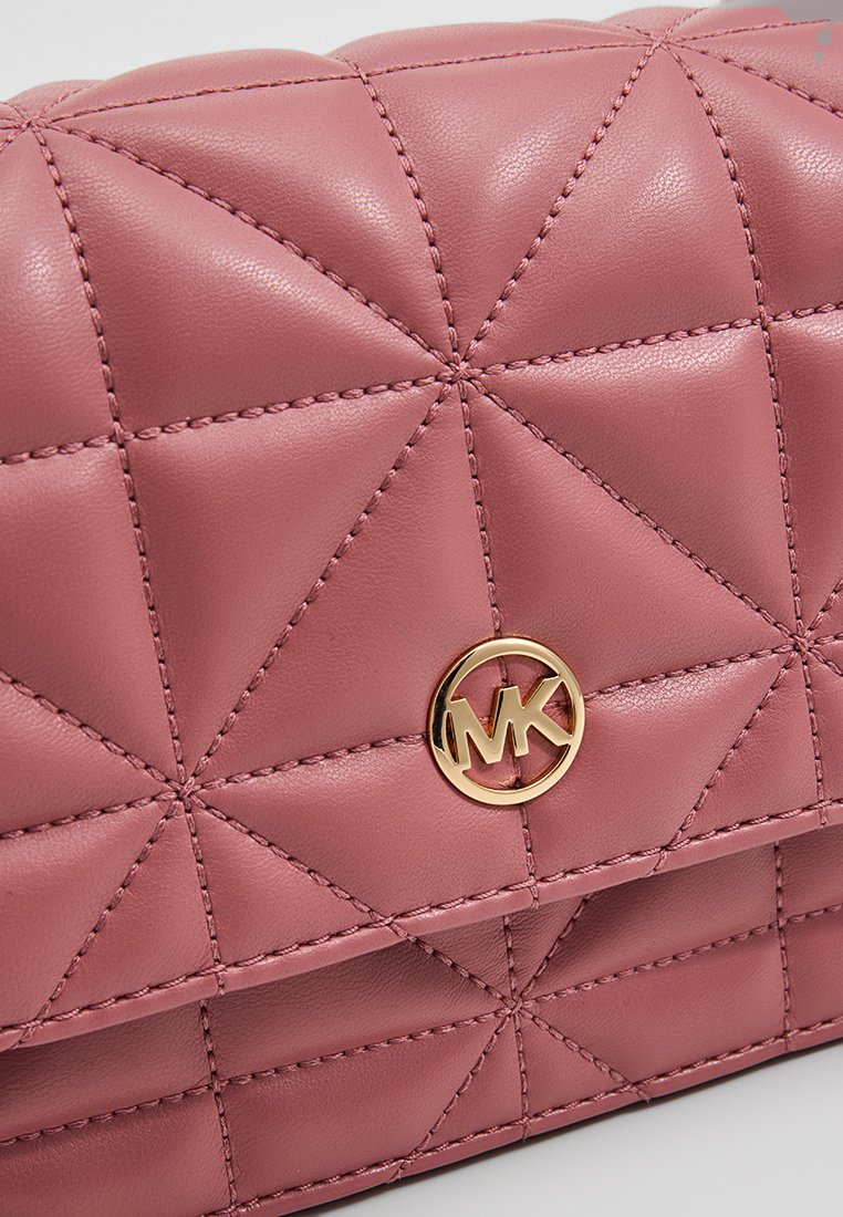 Sac à main en cuir rose matelassé avec un logo circulaire doré et des détails de coutures géométriques, affichant une texture lisse et une forme structurée.