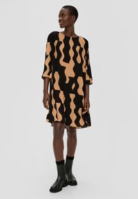 Zwarte jurk met korte mouwen en een bruine abstracte print. Gemaakt van geplooide stof, heeft een losse pasvorm en een ronde halslijn.