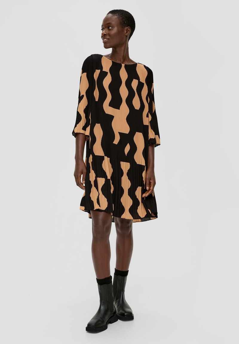 Zwarte jurk met korte mouwen en een bruine abstracte print. Gemaakt van geplooide stof, heeft een losse pasvorm en een ronde halslijn.