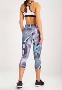 Leggings capri de cintura alta y ceñidos al cuerpo, con un patrón geométrico multicolor en azul, gris y negro, fabricados en un material liso y elástico.