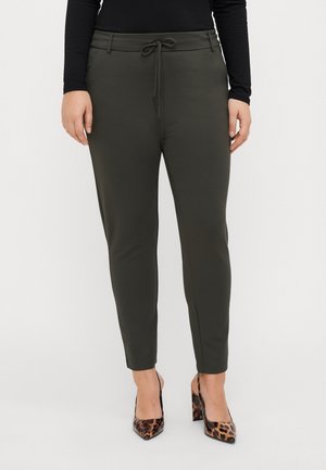 Woman wearing olive green slim-fit pants with drawstring waist and leopard print high-heeled shoes, standing against a plain background.