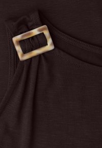 Tissu brun foncé avec une boucle rectangulaire en écaille formant des plis froncés près de l'encolure.