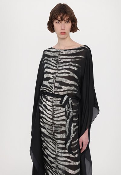 Rochie stratificată alb-negru cu model zebra, având decolteu în bărcuță, detalii cu nasturi și un accent legat la talie. Material ușor.