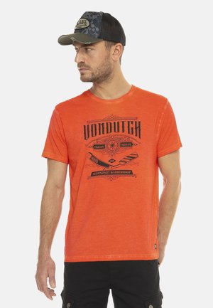T-shirt orange avec un col rond, présentant un imprimé graphique noir pour "VON DUTCH" et des accents sur le thème des barbers. Tissu en coton texturé.