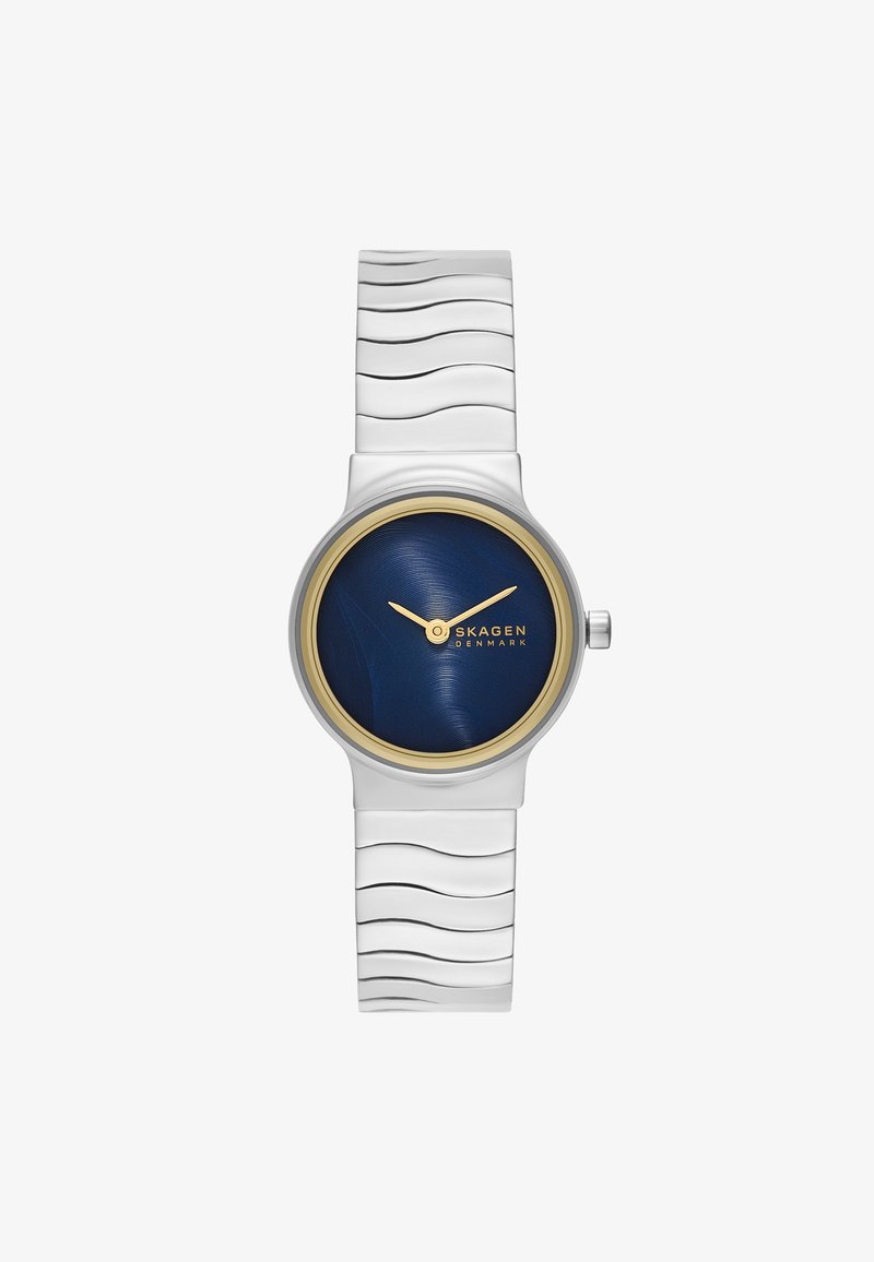 Runde Skagen-Uhr mit dunklem blauen Ziffernblatt, goldenen Akzenten und silbernem Metallarmband mit gewellter Textur. Einfache Markierungen und Zeiger.