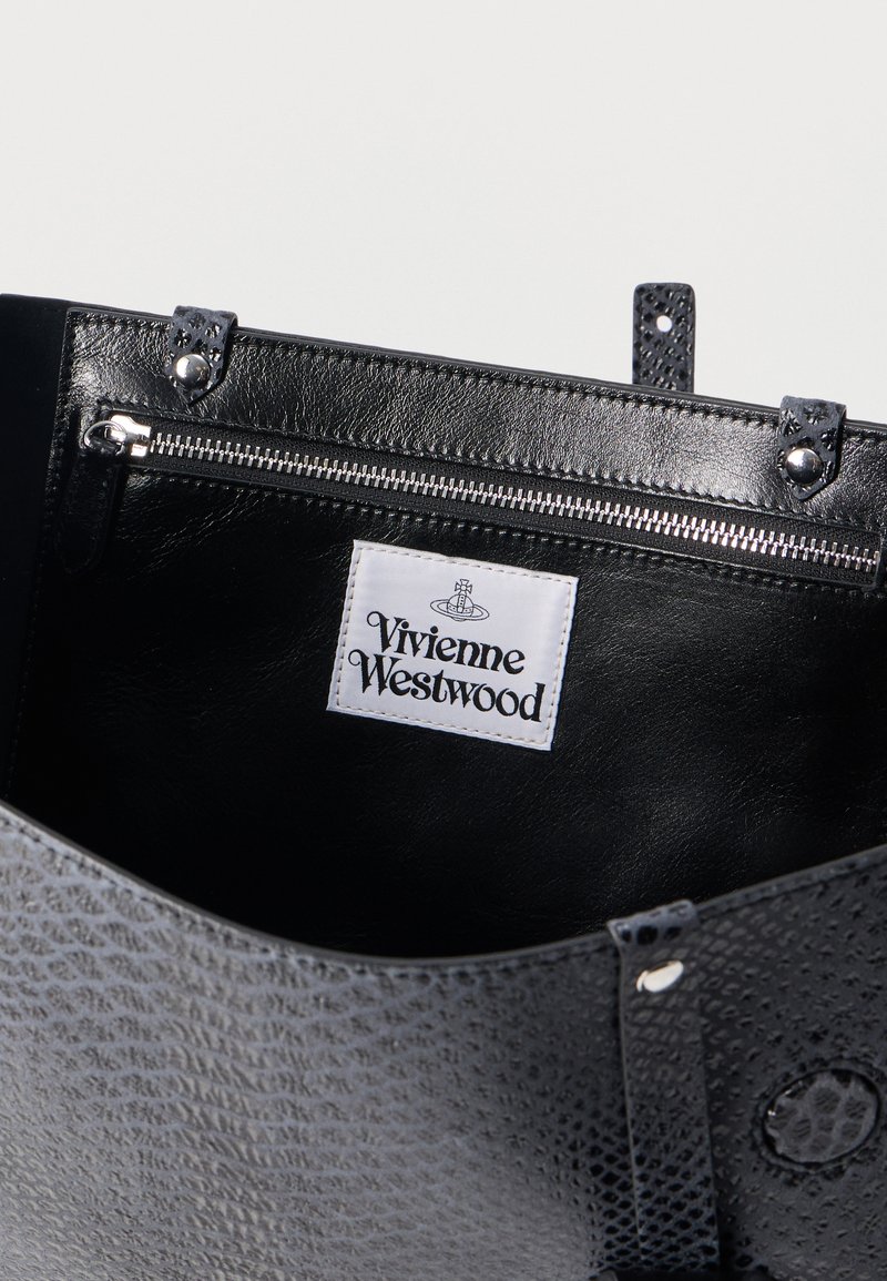 Interno di una borsa nera testurizzata che mostra una tasca con cerniera con un'etichetta di marca Vivienne Westwood bianca.