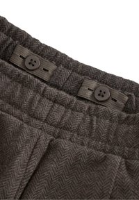 Ciemnobrązowa tkanina w wzór houndstooth z bliska, z fakturowaną powierzchnią, z guzikiem i elastycznym paskiem w talii.