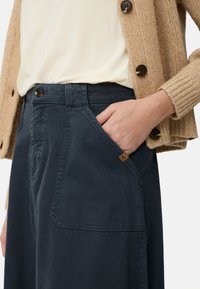 Marineblauwe wijde broek van een katoenmix, met een zijzak en een klein logolabel bij de tailleband. Gestructureerde stof.